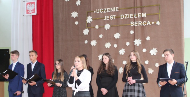 Zdjęcie z akademii z okazji Dnia Edukacji Narodowej przedstawiające śpiewającą grupkę młodzieży