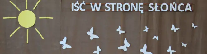 Zdjęcie przedstawia fragment dekoracji na uroczystości zakończenia roku, po lewej słońce, u góry napis i latające motylki