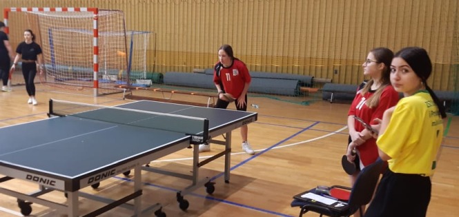 Zdjęcie przedstawia kilka dziewcząt grających w tenisa stołowego