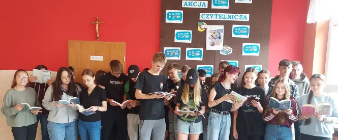 Grupa młodzieży z książkami pod napisami promującymi akcję czytelniczą