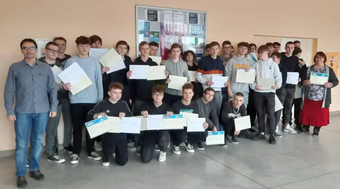 Grupa młodzieży wraz z dyrekcją i nauczycielem prezentuje otrzymane certyfikaty Cisco