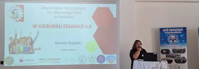 Dyrektor szkoły przemawia na konferencji z ekranem w tle