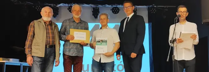 Uczeń Jakub wraz z organizatorami na scenie odbierający nagrodę