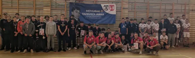 Uczestnicy Memoriału siatkarskiego Z plakatem M. Jarka w tle