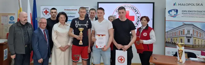 Szkolna drużyna na Mistrzostwach Pierwszej Pomocy z pucharem i organizatorami