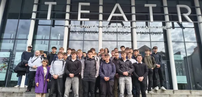 Grupa młodzieży wraz z opiekunami na schodach przed teatrem