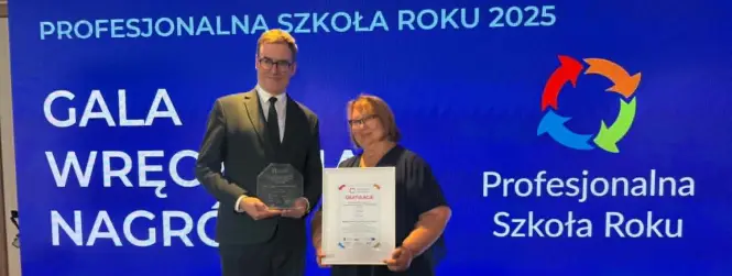Pani Dyrektor z dyplomem i mężczyzną ze statuetką, w tle baner