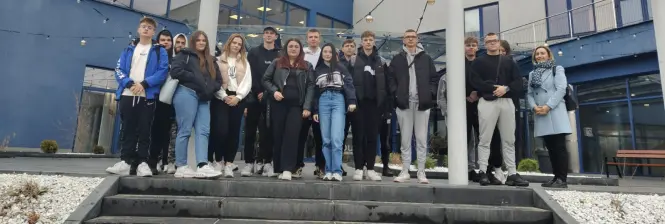 Młodzież z opiekunem przed siedzibą Wyższej Szkoły Biznesu 