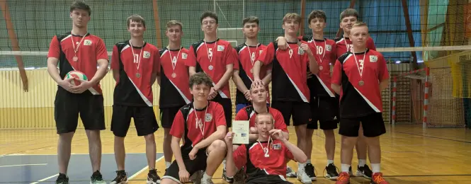 Drużyna siatkarzy z naszej szkoły stoi pod siatką w zwartej grupie